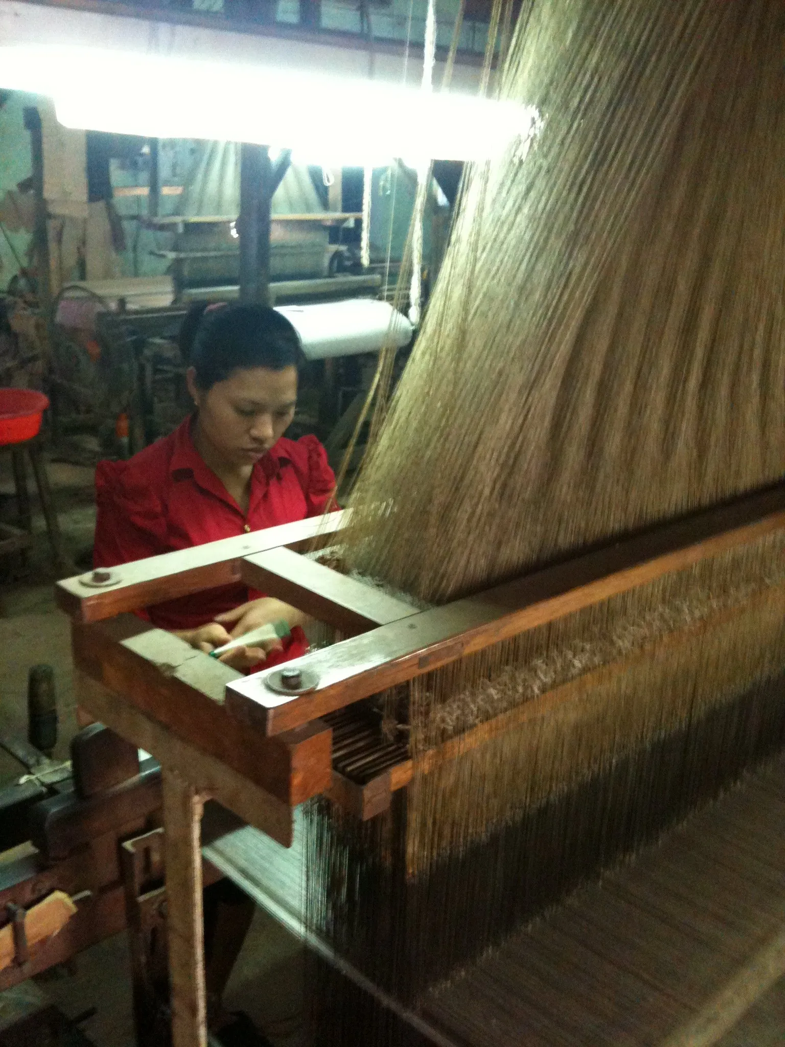 Ảnh chụp người thợ đứng bên khung dệt lụa Jacquard trong xưởng ở làng Vạn Phúc